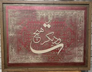 تابلو دیواری پتینه‌کاری شده با زمینه سنتی قرمز و خوشنویسی برجسته روی تخته با قاب طرح چوب